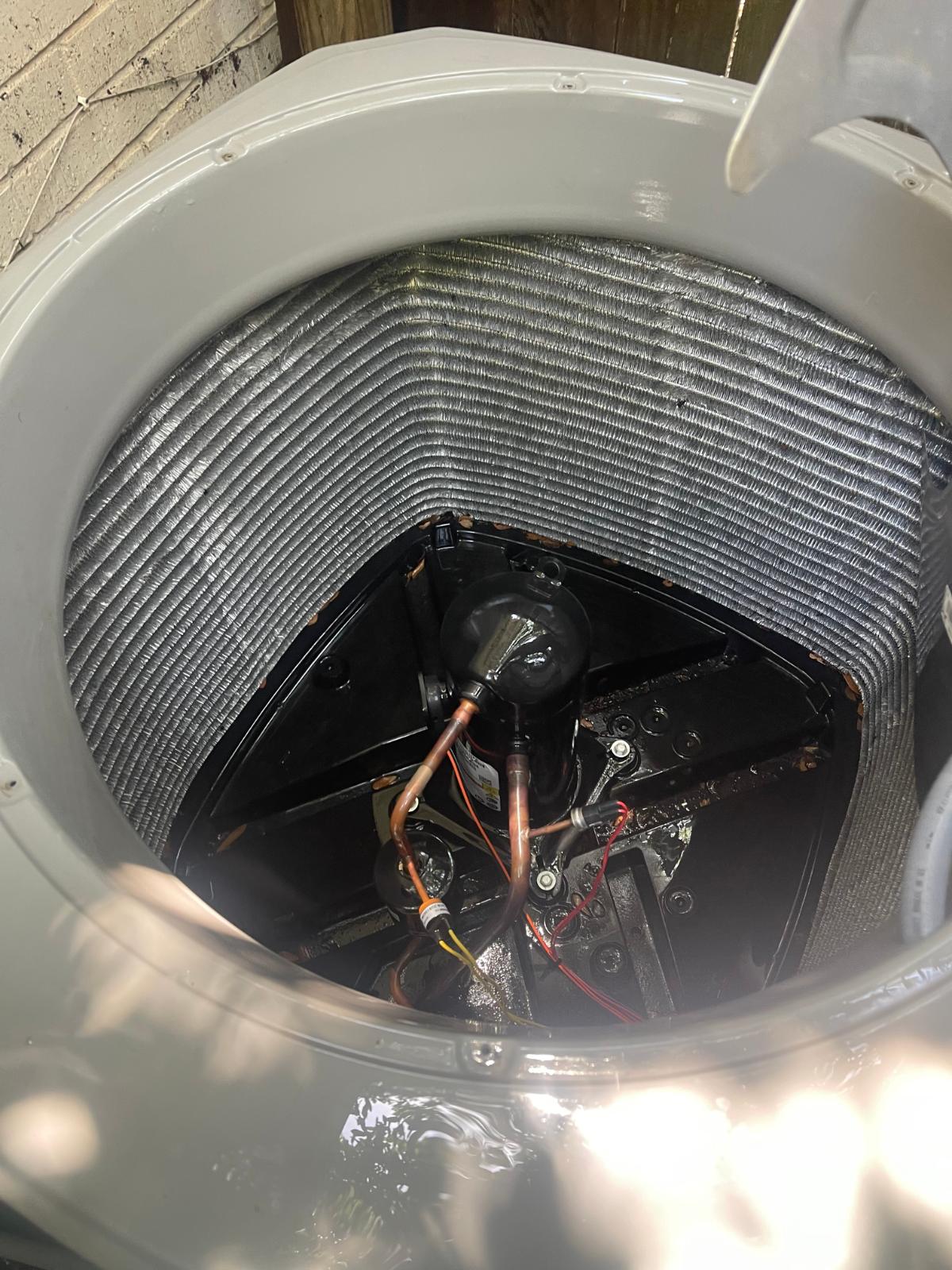 Close-up of condenser compressor and electrical connections during inspection