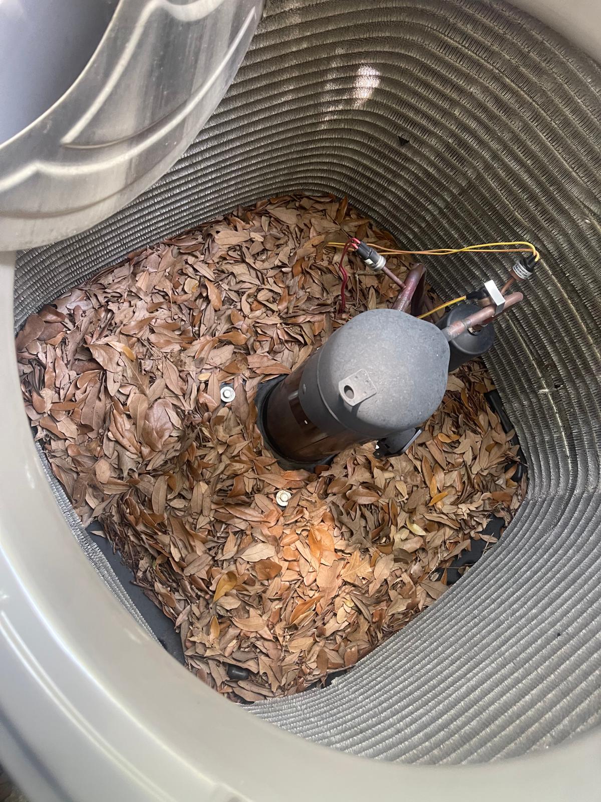 AC condenser coil clogged with leaves and debris before cleaning
